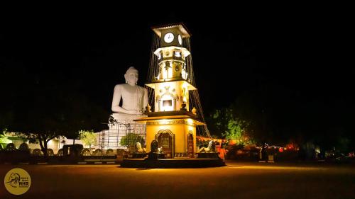 a large clock tower with a statue in front of it at National Holiday Resort in Mahiyangana