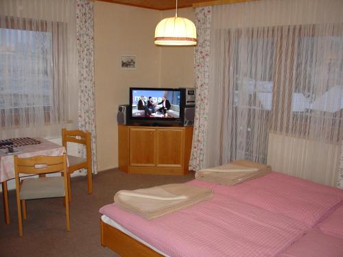 a bedroom with a bed and a tv and a table at Landhaus Dickhardt in Schladming