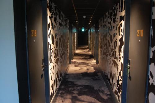 an empty hallway with white walls and a dark corridor at Hotel the Match in Eindhoven