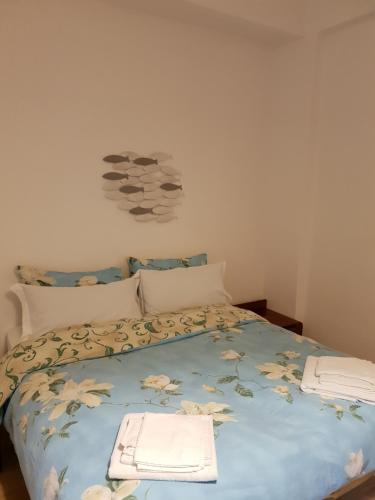 a bed with a blue comforter with towels on it at La casa di "Bella" in Milazzo