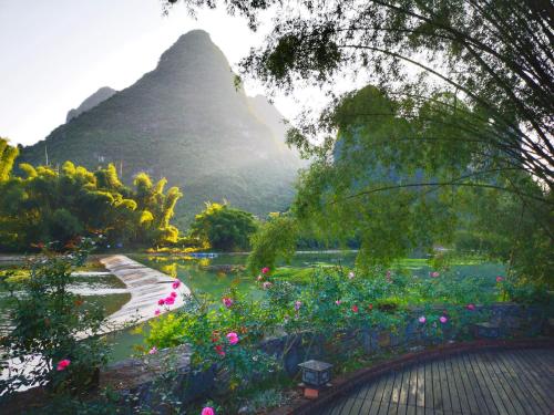 a view of a garden with flowers and a mountain at The Apsara Lodge-Airport or TS Free pick-up over 3 nights in Yangshuo