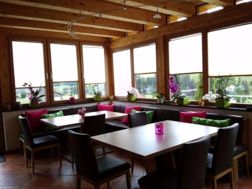 een eetkamer met tafels, stoelen en ramen bij Lungau Apartment - Ferienwohnung Haus Esl in Hintergöriach