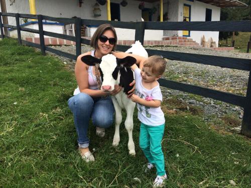 a woman and a child standing next to a cow at Hotel Bariloche in Santa Rosa de Cabal