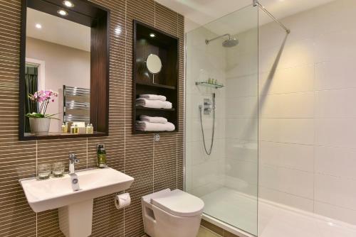 een badkamer met een douche, een toilet en een wastafel bij Fraser Suites Queens Gate in Londen