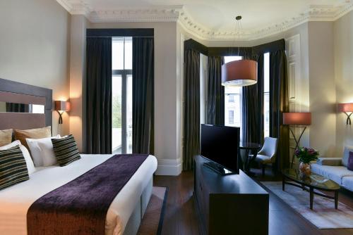 a bedroom with a large bed and a living room at Fraser Suites Queens Gate in London