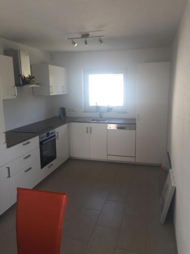 a kitchen with white cabinets and a red chair in it at Mara in Bad Nauheim