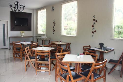 a restaurant with tables and chairs and a tv at Hotel Recanto dos Ipes in Frutal