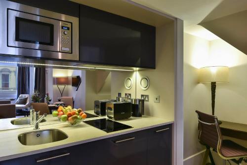 a kitchen with a stove top oven and a microwave at Fraser Suites Queens Gate in London