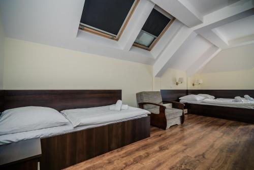 a room with two beds and a chair in it at Pensjonat pod Samowarem in Tylicz