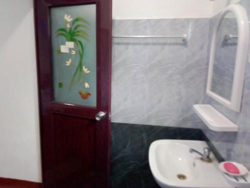 un baño con lavabo y una puerta con una pintura. en Ocean edge villa, en Midigama East
