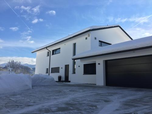 a white house with a garage in the snow at Ferienwohnung Black White in Raubling