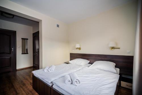 a bedroom with a bed with white sheets and towels at Pensjonat pod Samowarem in Tylicz