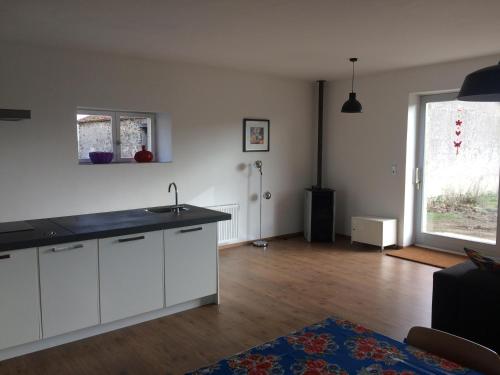 a kitchen with white cabinets and a hard wood floor at GÎTE Les Buis in Bussière-Portevine