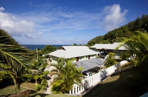 a house with a white fence and the ocean at Surfers Beach Self Catering Chalets in Takamaka