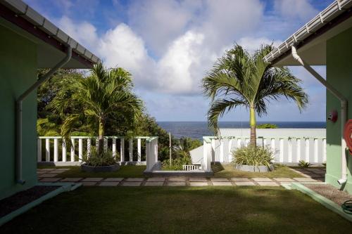 a house with a white fence and palm trees at Surfers Beach Self Catering Chalets in Takamaka
