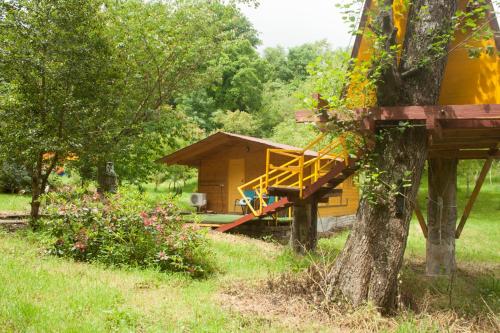 a small yellow cabin in a field with a tree at Cabañas aloños sociedad limitada in Aloños