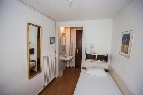 um pequeno quarto branco com uma cama e um lavatório em Hotel St. Gervais em Genebra