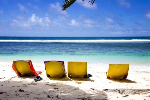 three chairs sitting in the sand on the beach at Surfers Beach Self Catering Chalets in Takamaka