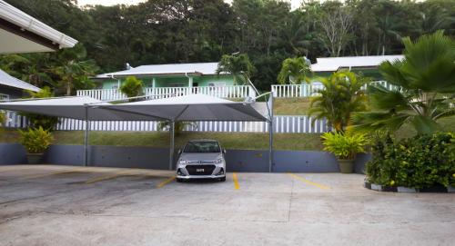 a small car parked in a parking lot under an umbrella at Surfers Beach Self Catering Chalets in Takamaka