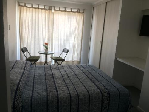 a bedroom with a bed and a table and chairs at Hospedaje Amunátegui in Iquique