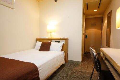 a hotel room with a bed and a desk at Shin-Osaka Sunny Stone Hotel in Osaka
