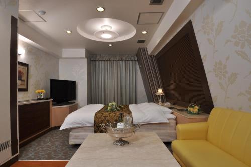 a hotel room with a bed and a television at HOTEL U's 香櫨園 in Nishinomiya