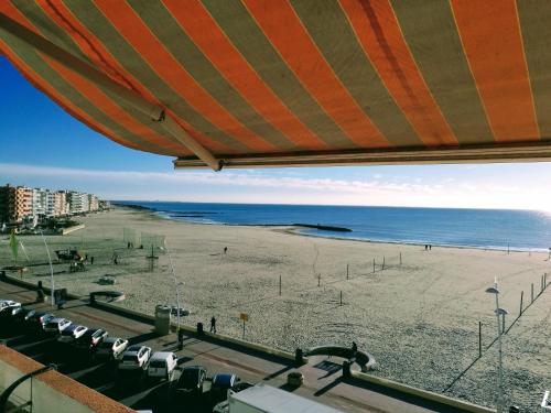 - une plage avec un grand parasol et l'océan dans l'établissement Le Saint Roch - belle vue mer en plein centre ville, à Palavas-les-Flots