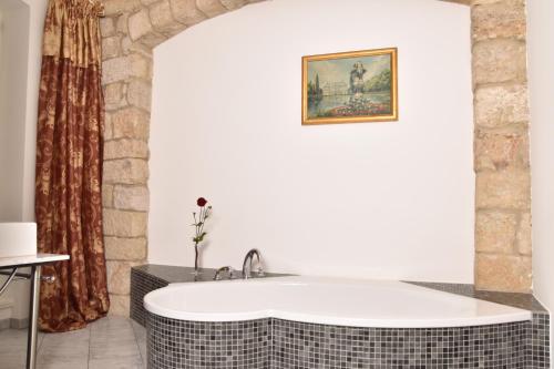 a bath tub in a bathroom with a painting on the wall at Apartmenthaus Albrechtsburg in Bad Schandau