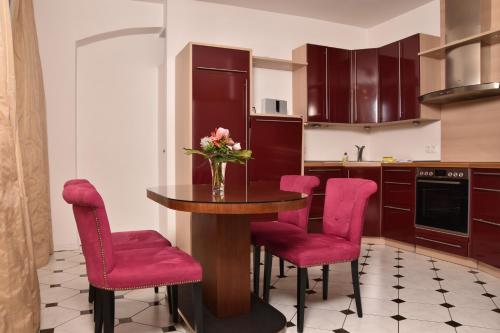 a kitchen with a table and pink chairs at Apartmenthaus Albrechtsburg in Bad Schandau