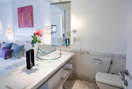 a white bathroom with a sink and a mirror at The Ashtan Sarovar Portico in New Delhi
