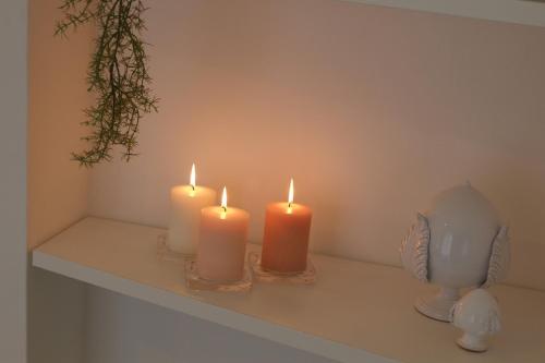 three candles sitting on a table with a vase at Via Ricasoli 8 in Ostuni