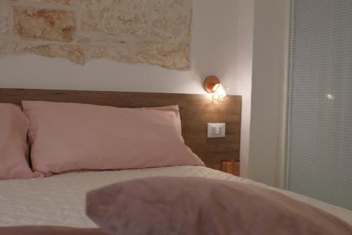 a bed with a white pillow and a light on the wall at Via Ricasoli 8 in Ostuni