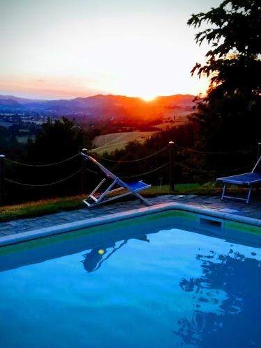 a swimming pool with the sunset in the background at Agriturismo Alla Vecchia Quercia in Pergola