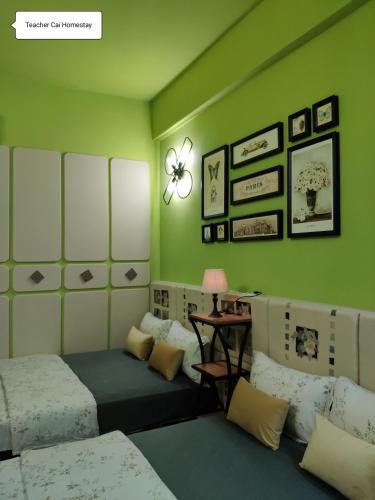 a green room with two beds and a table at Teacher Cai Homeestay in Xiaoliuqiu