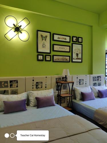 a green room with two beds and a ceiling fan at Teacher Cai Homeestay in Xiaoliuqiu