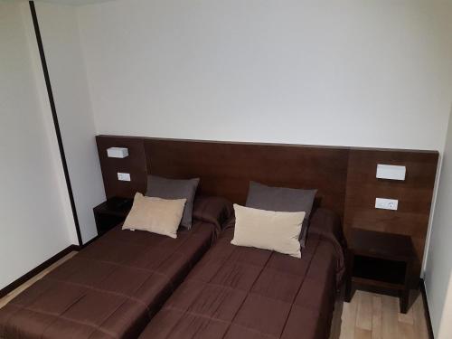 a brown couch with two white pillows on it at Complejo O Piñeiral A Fonsagrada in Fonsagrada
