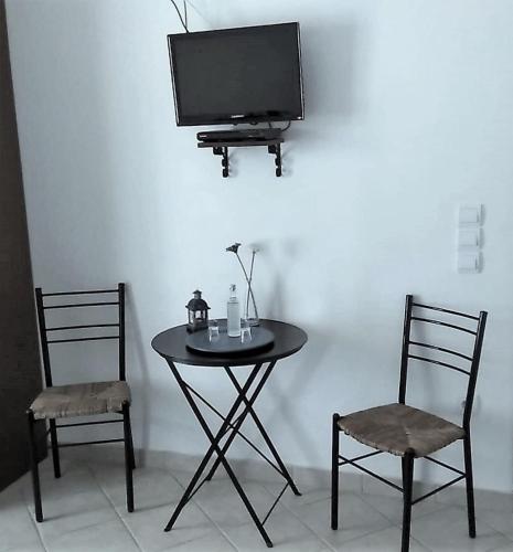 a table with two chairs and a tv on a wall at Stella's Home in Koufonisia