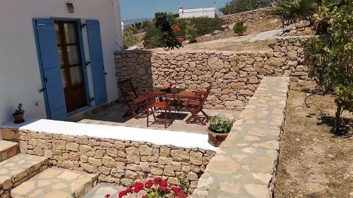 a patio with a table and chairs and a stone wall at Stella's Home in Koufonisia