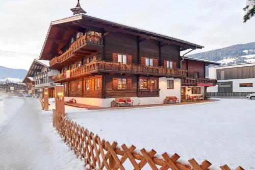 a wooden building with a fence in the snow at Bio-Pension Bliem in Altenmarkt im Pongau