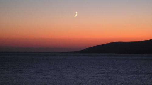 a moon in the sky over the ocean at sunset at Stella's Home in Koufonisia