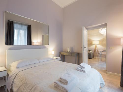 a white bedroom with a large bed and a mirror at Ara Pacis Luxury Apartments by CapriRooms in Rome