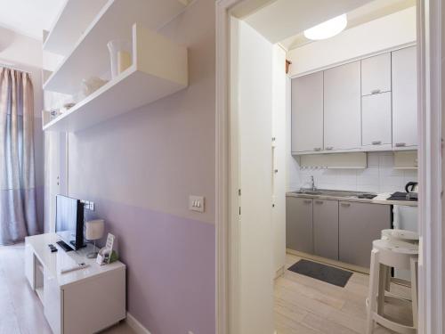 une petite cuisine avec des placards blancs et une télévision dans l'établissement Ara Pacis Luxury Apartments by CapriRooms, à Rome