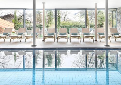 a room with a pool with chairs and water at Hotel Das Stachelburg in Parcines