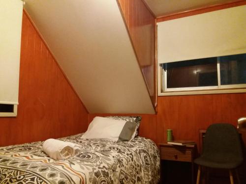 a bedroom with a bed and a window and a chair at Eco Nautic Hostel in Valdivia