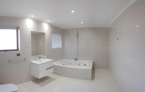 a white bathroom with a tub and a sink at Pinares de Higuerillas in Maitencillo
