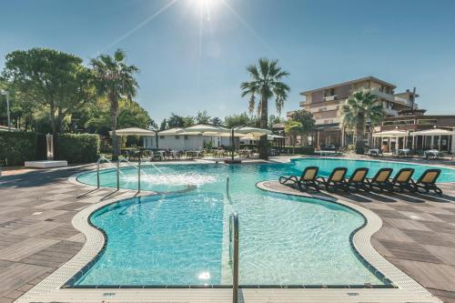 una gran piscina con sillas y palmeras en Hotel Acquario en Vasto