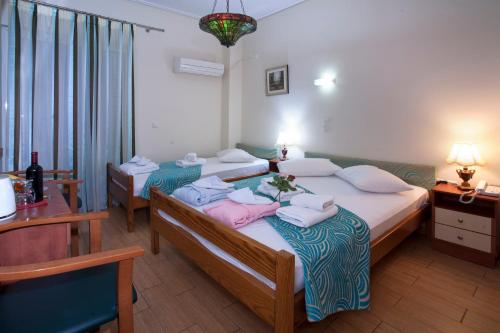 a hotel room with two beds and a table at Hotel Loutraki in Loutraki