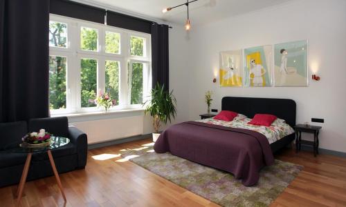 a bedroom with a bed and a couch and windows at Sopot Ostsee Apartments in Sopot