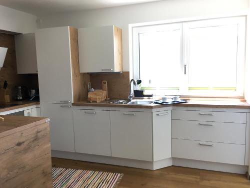 a kitchen with white cabinets and a window at Koflers Ferienwohnungen in Oberperfuss