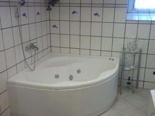 a white tub in a bathroom with a tile wall at Zum alten Schusterhaus in Bad Endbach